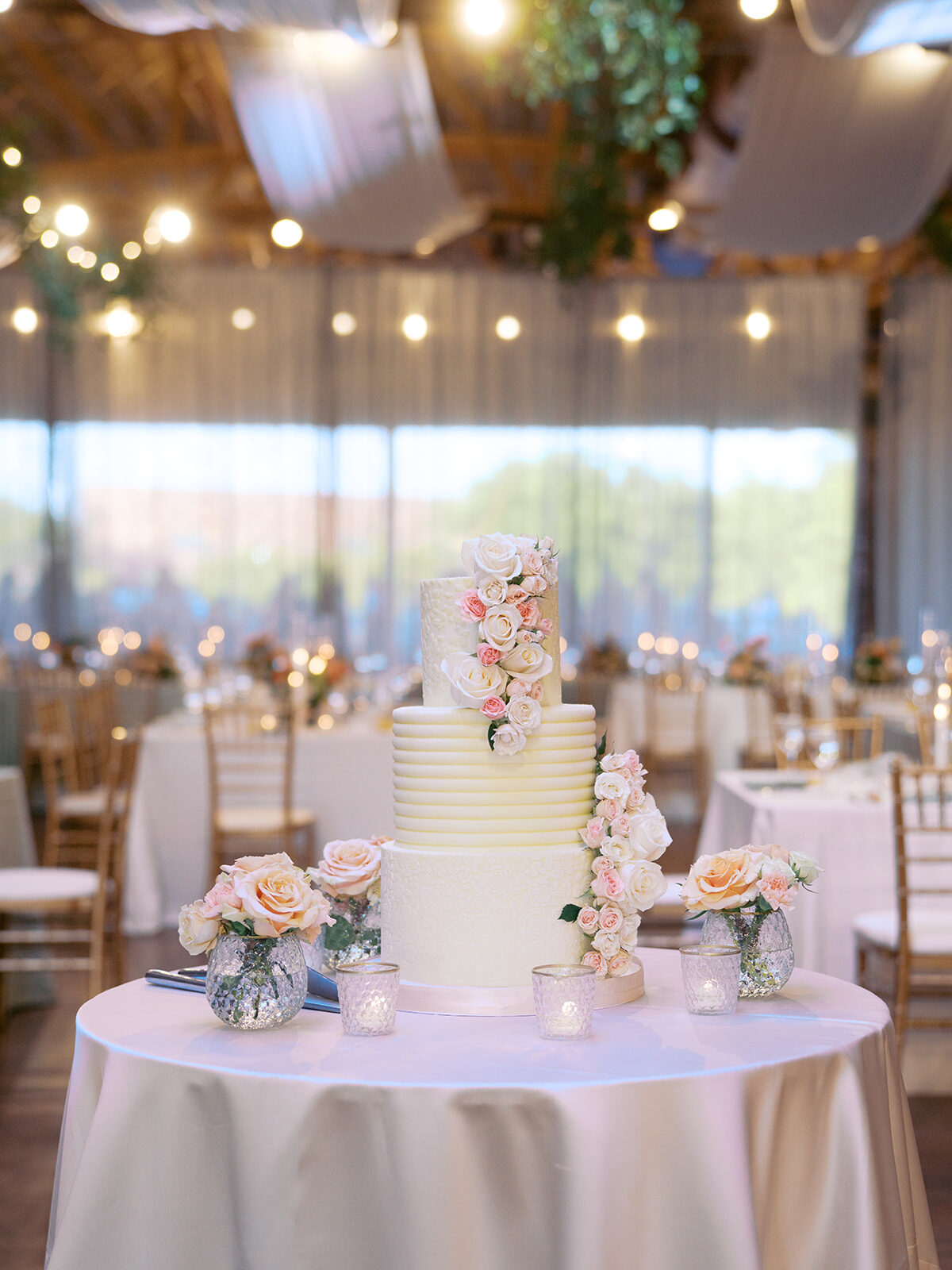 Tiered white wedding cake with cascading roses in an elegant venue